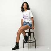 Person wearing a white t-shirt with 'focus on the good' text in purple outdoors.