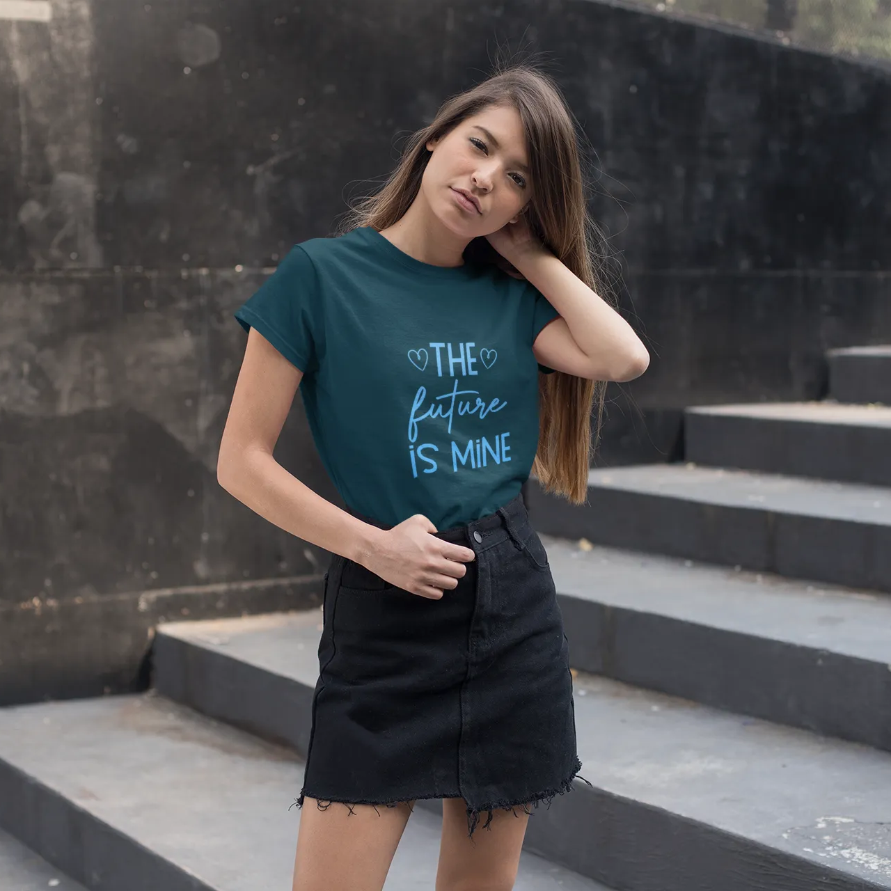 Woman wearing a teal t-shirt with text standing on steps outdoors