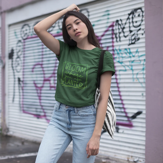 Woman wearing a green t-shirt with text, standing in front of a graffiti-covered wall.