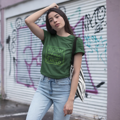 Woman wearing a green t-shirt with text, standing in front of a graffiti-covered wall.
