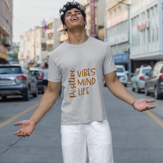 Man wearing a t-shirt with 'Positive Vibes Mind Life' on a city street.