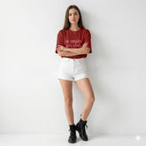 Woman wearing a red t-shirt with text and white shorts on a plain background