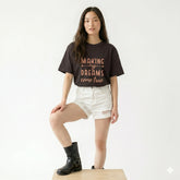 Person wearing a black t-shirt with text and white shorts on a white background