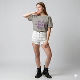 Woman wearing a gray t-shirt with a motivational quote on a plain background