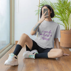 Person sitting on the floor taking a mirror selfie wearing a t-shirt with a motivational quote.