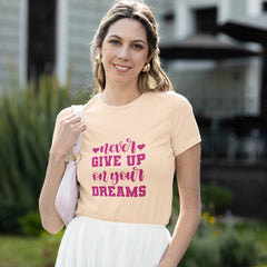 Woman wearing a peach t-shirt with motivational text, standing outdoors.