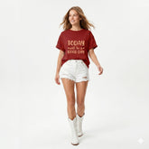 Woman wearing a red 'Today will be a good day' t-shirt with white shorts and boots on a light gray background