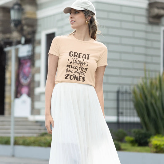 Woman wearing a beige t-shirt with text and a white skirt outdoors.