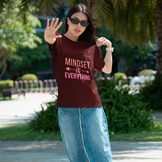 Woman wearing a maroon t-shirt with 'MINDSET is EVERYTHING' text in an outdoor setting.