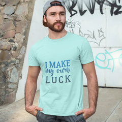 Man wearing a light blue t-shirt with 'I Make My Own Luck' text, standing against a graffiti-covered wall.