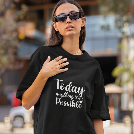 Woman wearing a black t-shirt with 'Today anything is possible' text on a street.
