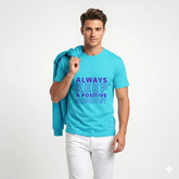 Person wearing a turquoise t-shirt with motivational text on a city street.