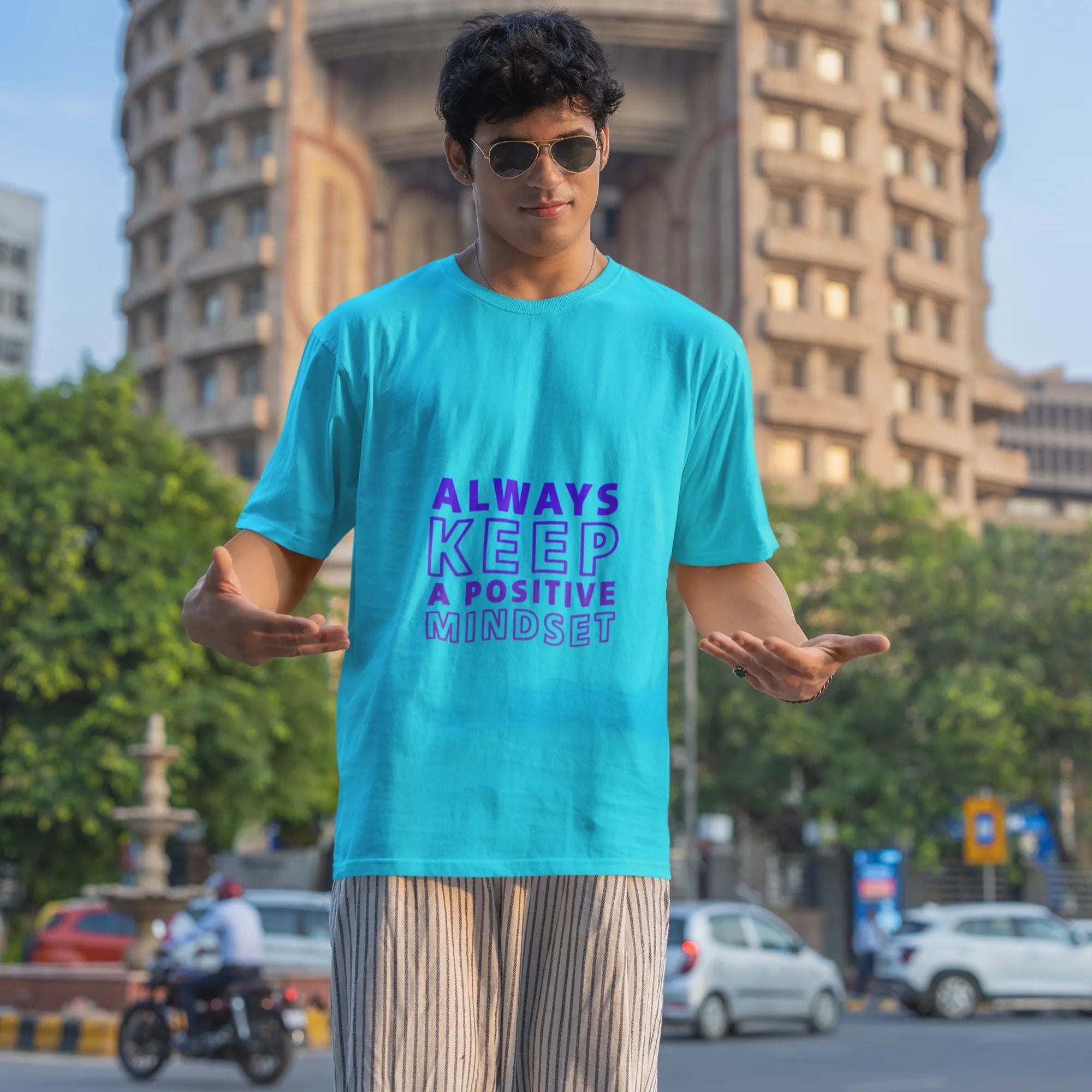Person wearing a blue t-shirt with a motivational quote in an urban setting