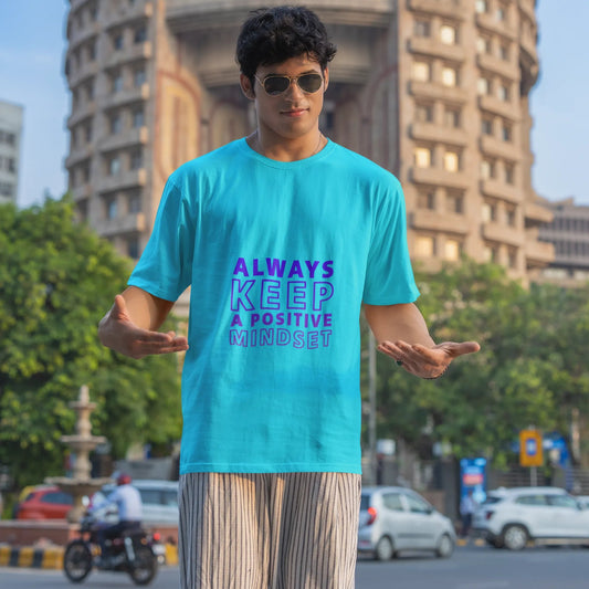 Person wearing a blue t-shirt with a motivational quote in an urban setting