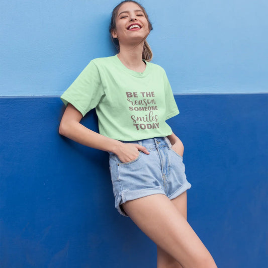 Person wearing a green t-shirt with text against a blue wall