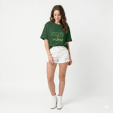 Person wearing a green 'cozy vibes' t-shirt with arms raised outdoors.