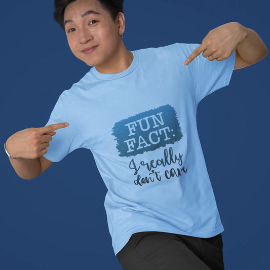 Person wearing a light blue t-shirt with a humorous design on a solid background