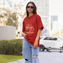 Woman wearing a red oversized t-shirt and ripped jeans on a city street.