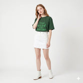 Woman wearing a green t-shirt with text and a white skirt on a white background