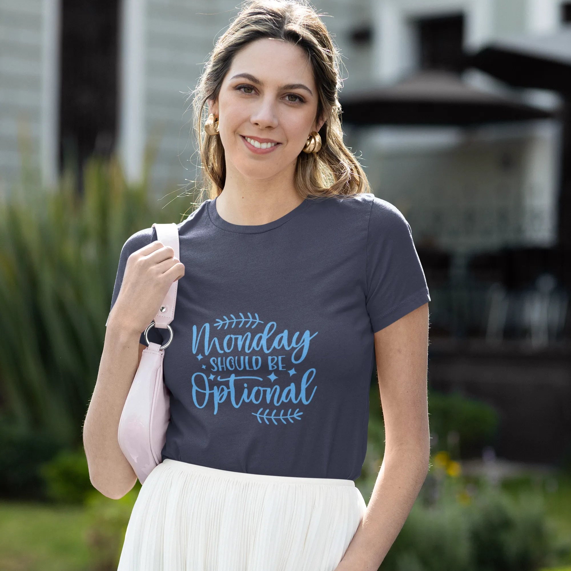 Woman wearing a t-shirt with 'Monday should be optional' text outdoors.