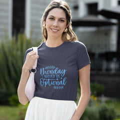 Woman wearing a t-shirt with 'Monday should be optional' text outdoors.