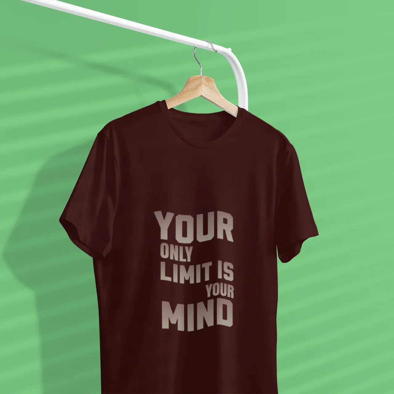 Brown t-shirt with 'Your only limit is your mind' text on a hanger against a green background