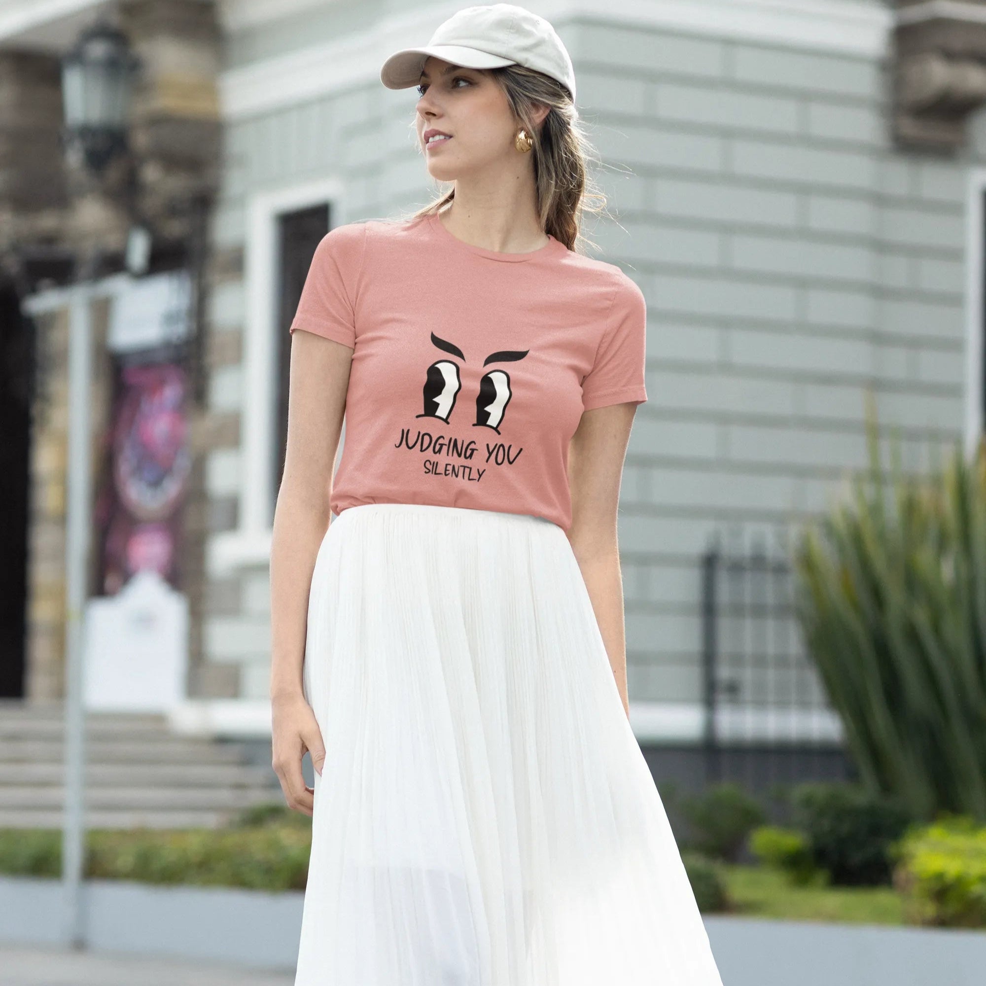 Woman wearing a pink t-shirt with a graphic design and text, standing outdoors.