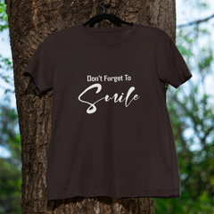 Brown t-shirt with 'Don't Forget To Smile' text hanging on a tree