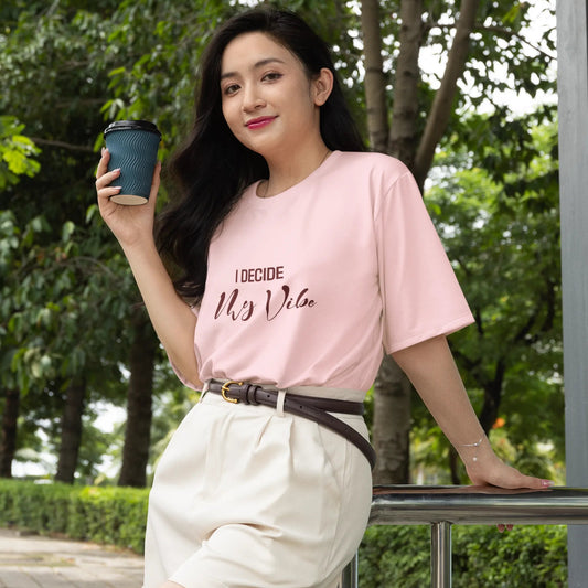 Woman wearing a pink t-shirt with text, holding a coffee cup outdoors.