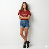 Woman wearing a red t-shirt with text and blue shorts on a white background