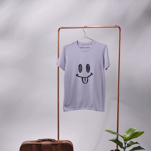 Light purple t-shirt with smiley face design on a hanger, next to a brown leather suitcase and potted plant against a gray background.