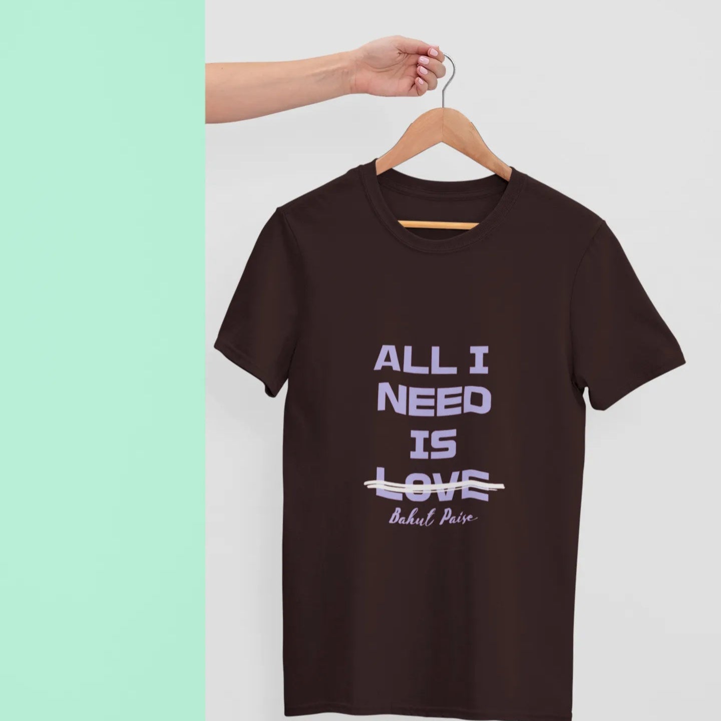 Brown t-shirt with 'All I Need is Love' text on a hanger against a light background