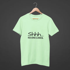 Light green t-shirt with 'Shhh... No one cares.' text on a dark background