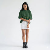 Woman wearing a green t-shirt with text and a white skirt on a white background