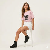 Woman wearing a pink t-shirt with text, white shorts, and black boots on a white background
