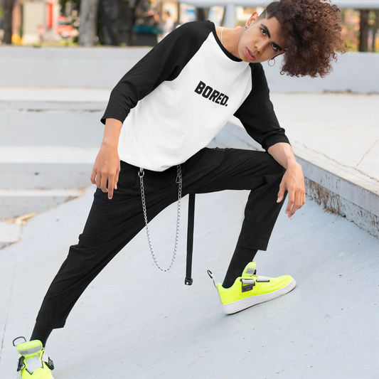 Person wearing a black and white shirt with 'BORED.' text, black pants, and bright yellow sneakers on a concrete surface.