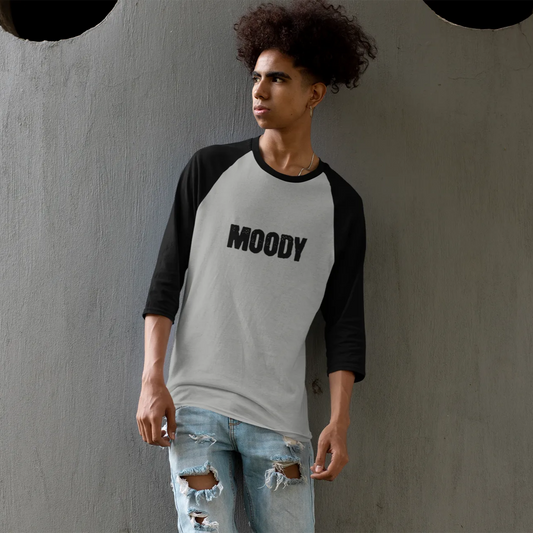 Person wearing a 'MOODY' shirt against a gray wall