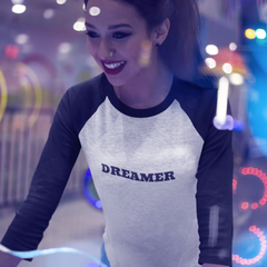 Woman wearing a shirt with 'DREAMER' text in a colorful, possibly amusement park setting.