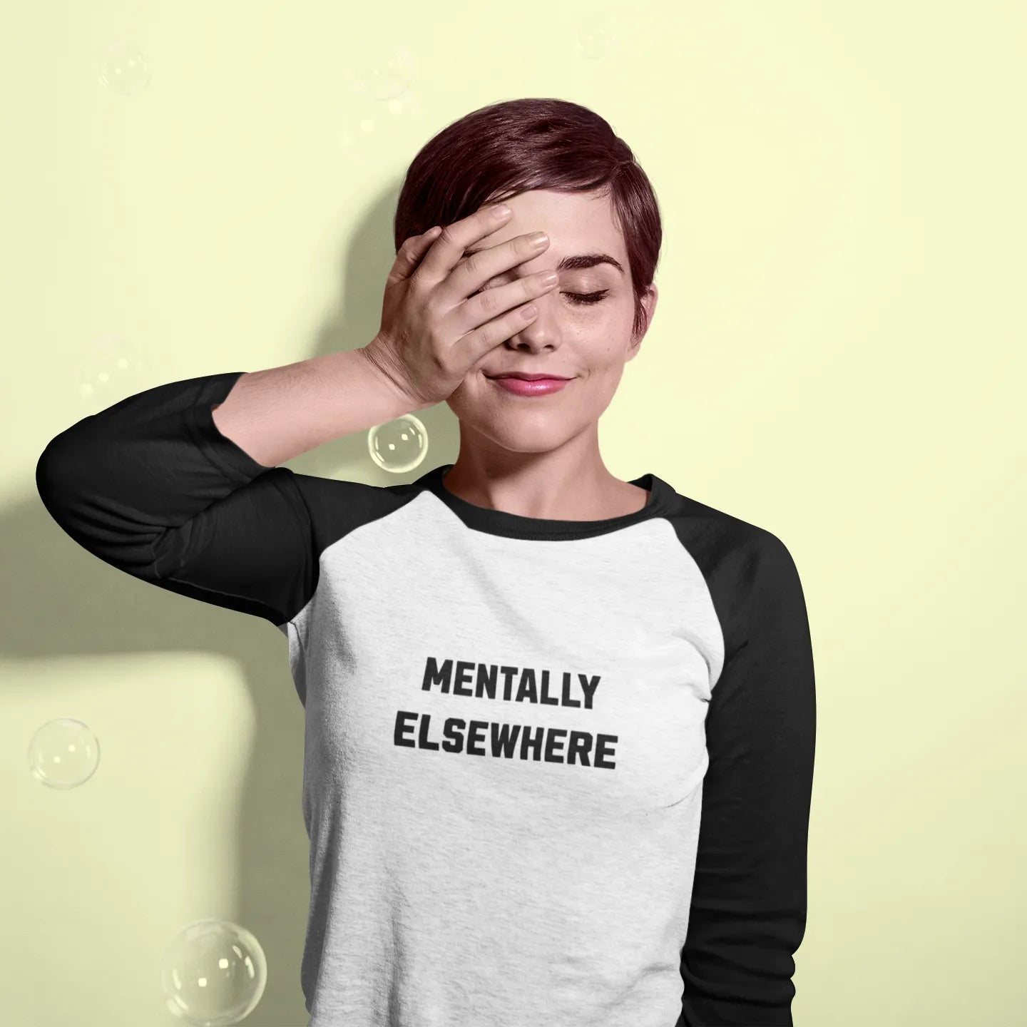 Person wearing a black and white baseball shirt with 'MENTALLY ELSEWHERE' text on a light yellow background