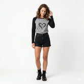 Woman wearing a gray long-sleeve shirt with a heart design and black shorts on a white background