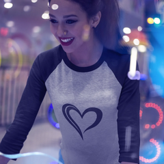 Woman wearing a shirt with a heart design in a colorful, possibly amusement park setting.