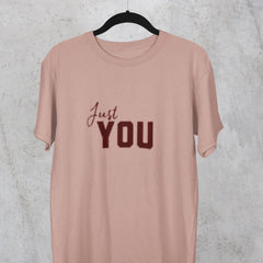 Pink t-shirt with 'Just YOU' text on a hanger against a textured gray background