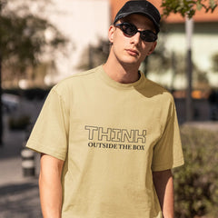 Person wearing a light green t-shirt with 'THINK OUTSIDE THE BOX' text, standing outdoors.