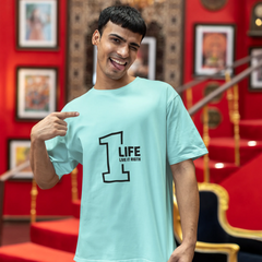 Man wearing a light blue t-shirt with '1 LIFE' design in a decorated room.