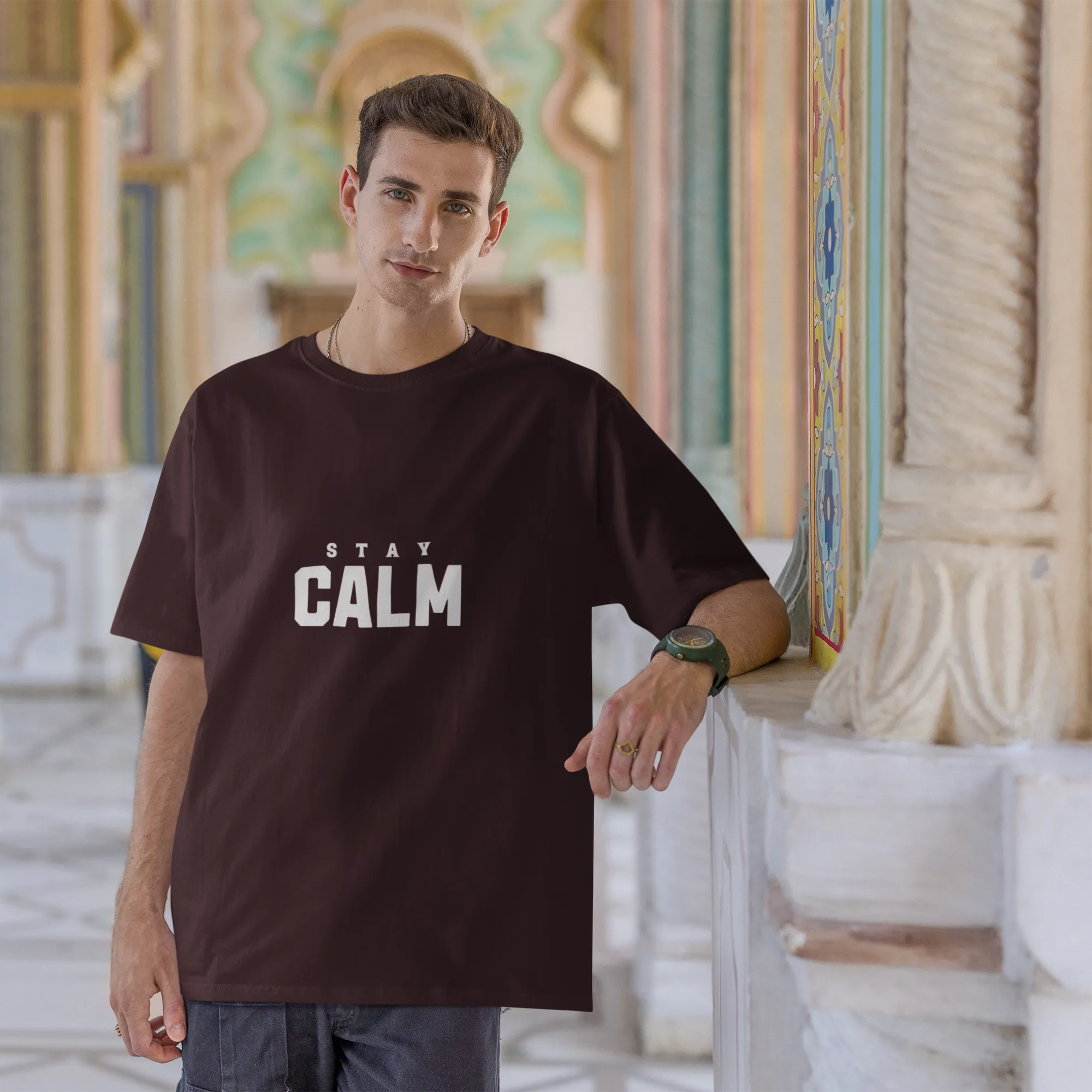 Man wearing a black t-shirt with 'Stay Calm' text in an ornate architectural setting