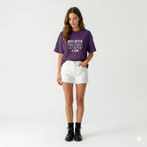 Woman wearing a purple t-shirt with 'BELIEVE YOU CAN' text on a white background