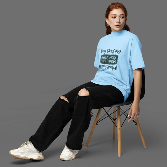 Person sitting on a chair wearing a light blue t-shirt with text and black pants.