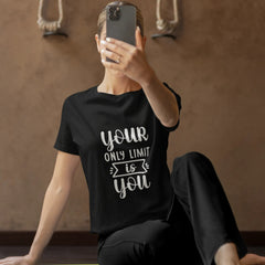 Person wearing a black t-shirt with motivational text, sitting on a yoga mat.