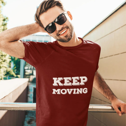 Man wearing a maroon t-shirt with 'KEEP MOVING' text, standing outdoors.