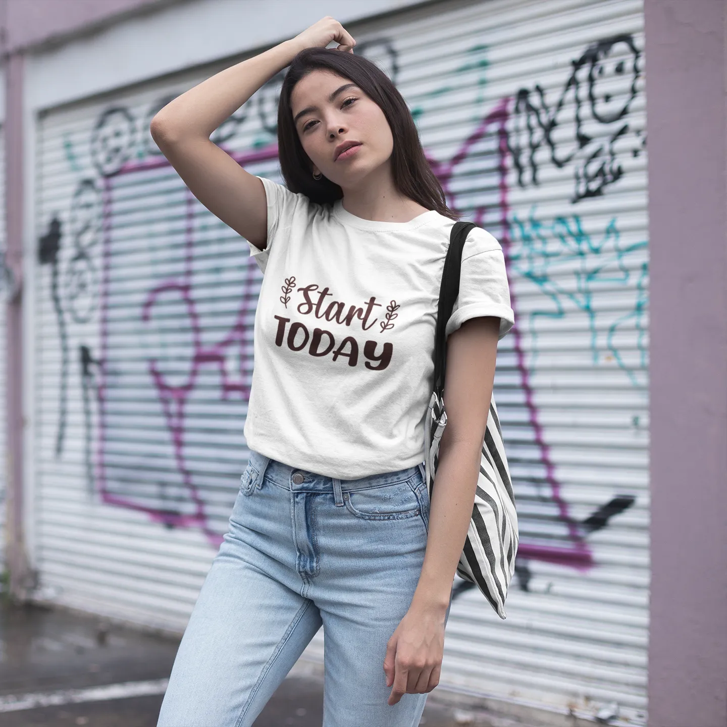 Woman wearing a white t-shirt with 'Start Today' text in front of a graffiti-covered wall.